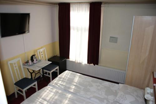 a bedroom with a bed and a table and a window at Hotel de Westertoren in Amsterdam