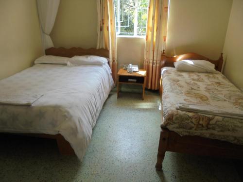 a bedroom with two beds and a table and a window at Adventist LMS Guest House & Conference Centre in Nairobi