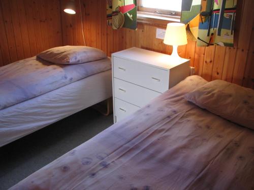 a bedroom with two beds and a night stand with a lamp at Guesthouse Húsid in Hlíðarendi
