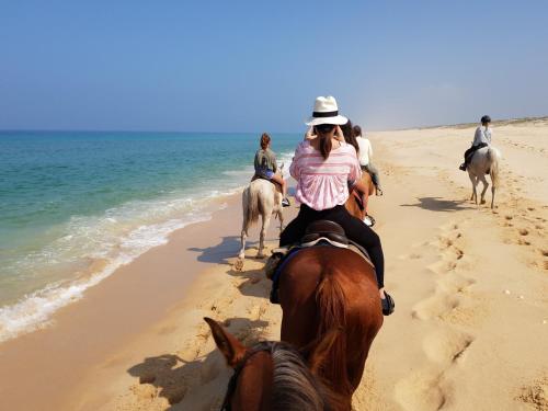 a group of people riding horses on the beach at Flow Rooms in Comporta