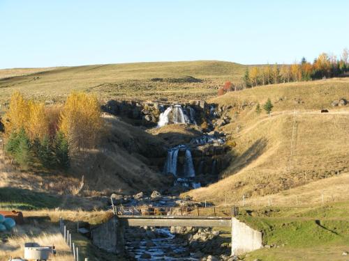 a waterfall on the side of a hill with a bridge at Guesthouse Húsid in Hlíðarendi