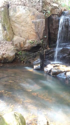 uma cascata numa piscina de água com pedras em Pousada Cachoeira em Serra Negra