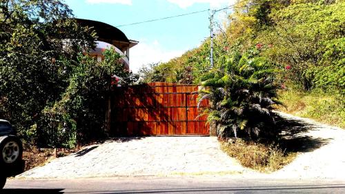 a driveway with a wooden fence in front of a house at Casa La Guaria in Sámara