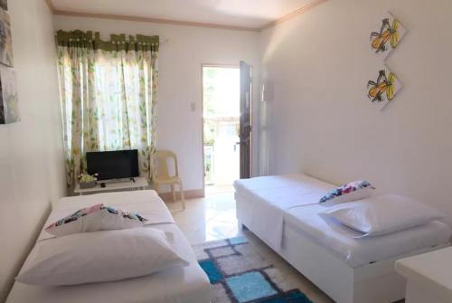 a white room with two beds and a television at RQS Hostel in Tacloban