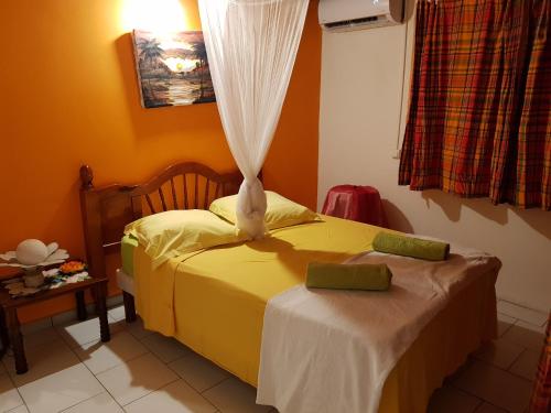 Un dormitorio con una cama amarilla y una ventana en Bel Appartement - proche des plages de Sainte Anne, en Sainte-Anne
