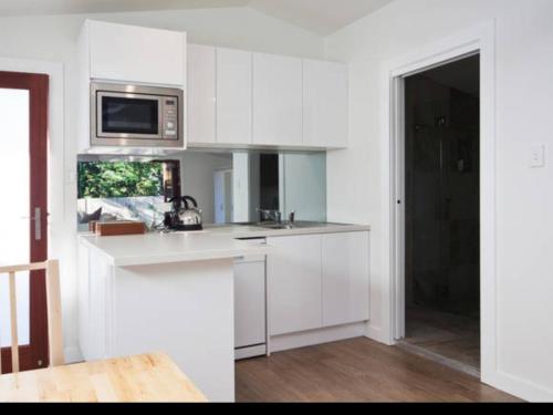 a kitchen with white cabinets and a microwave at Bijoux Beach House in Freshwater