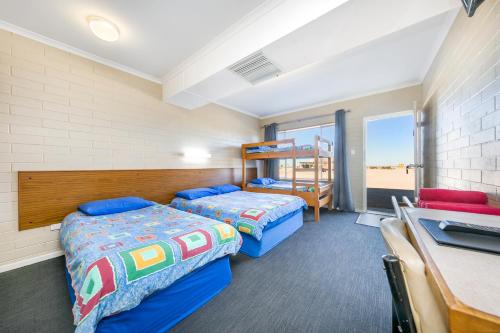 2 camas en una habitación con escritorio y litera en Nullarbor Roadhouse, en Nullarbor