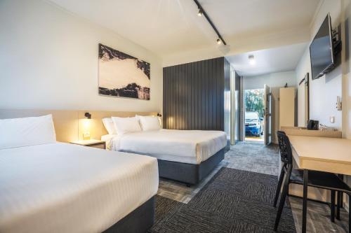 a hotel room with two beds and a desk at Nightcap at Keysborough Hotel in Keysborough