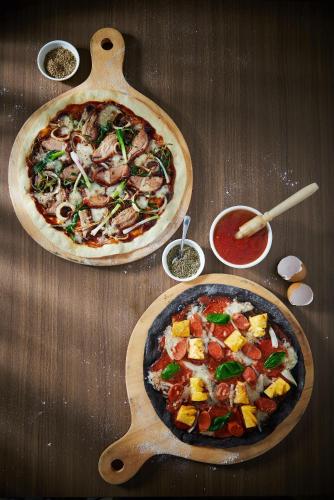 a wooden table with two pizzas on a table at Golden Tulip Holland Resort Batu in Batu
