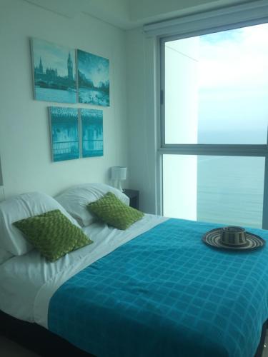 ein Schlafzimmer mit einem Bett mit einer blauen Decke und einem Fenster in der Unterkunft Beach front Apartament in Cartagena de Indias
