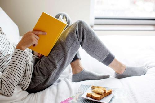 a person sitting on a bed reading a book at Hyatt Place Salt Lake City Downtown / The Gateway in Salt Lake City
