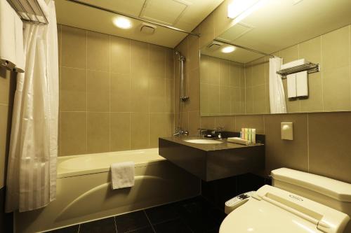 a bathroom with a tub and a toilet and a sink at Bridge Hotel Incheon Songdo in Incheon