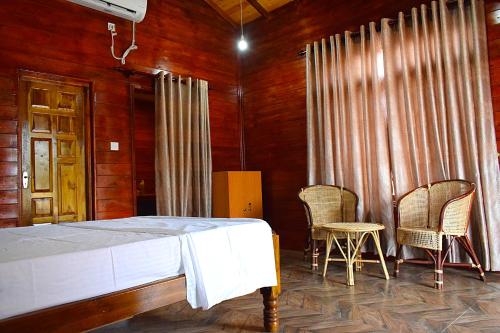 a bedroom with a bed and two chairs at Mithra Paradise Beach Hotel in Nilaveli