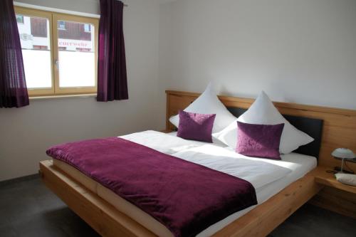 a bedroom with a bed with purple and white pillows at Ferienwohnungen Ellen Müller in Fischen