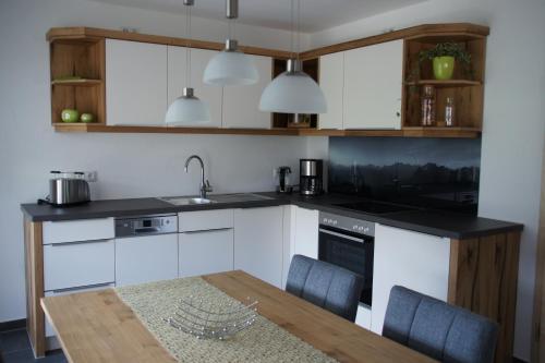 a kitchen with white cabinets and a wooden table at Ferienwohnungen Ellen Müller in Fischen