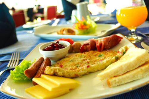 a plate of breakfast food on a table at Mithra Paradise Beach Hotel in Nilaveli