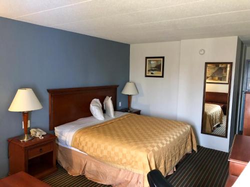 Habitación de hotel con cama y espejo en Knights Inn Dayton by Miller Lane, en Dayton