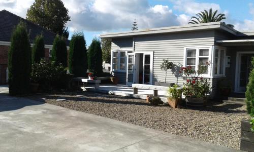 a small white house with a bench in front of it at Peachgrove in Hamilton