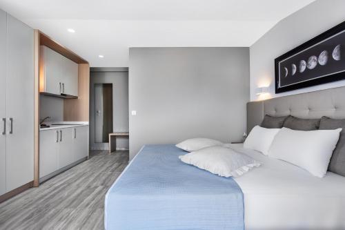 a bedroom with a large bed and a kitchen at Nymphes Deluxe Accommodation Pefkochori in Pefkohori
