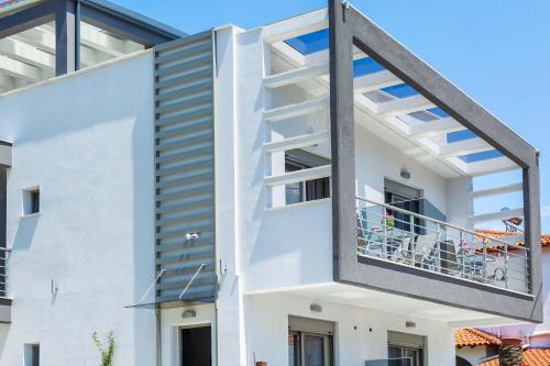a building with a balcony with a table on it at Nymphes Deluxe Accommodation Pefkochori in Pefkohori