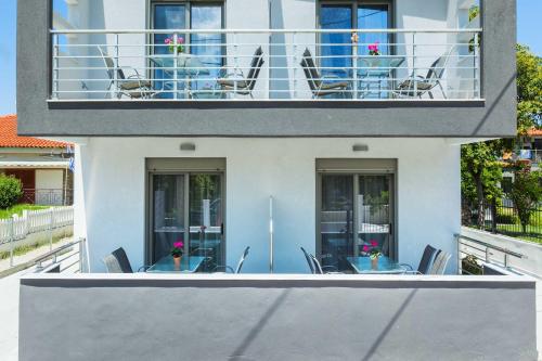 a balcony with chairs and tables on a building at Nymphes Deluxe Accommodation Pefkochori in Pefkohori