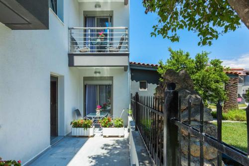 a white house with a balcony and a fence at Nymphes Deluxe Accommodation Pefkochori in Pefkohori