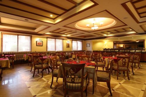 a restaurant with tables and chairs in a room at Beverly Hotel in Chennai