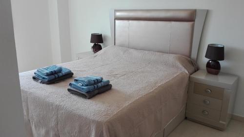Una cama con dos almohadas azules encima. en CALPE9A, en Calpe