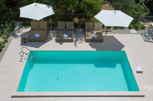 a swimming pool with two umbrellas and chairs and a pool at Villa Celeia in Krk