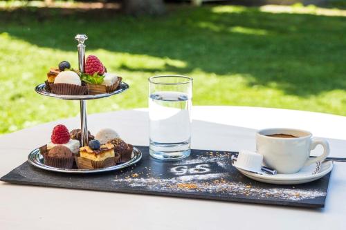 a tray of desserts on a table with a glass of water at Grand Hotel Sofia in Sofia