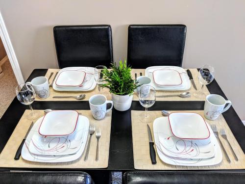 a black table with white plates and silverware on it at Quiet 2 Bed 2 Bath close to Westview Hospital in Stony Plain