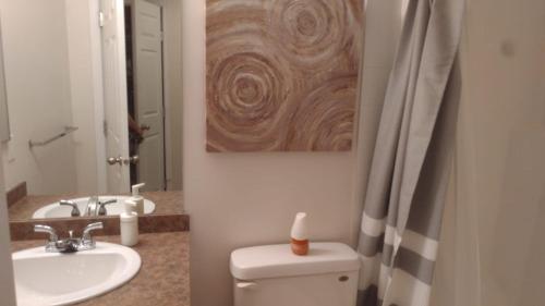 a bathroom with a toilet and a sink and a painting at Quiet 2 Bed 2 Bath close to Westview Hospital in Stony Plain