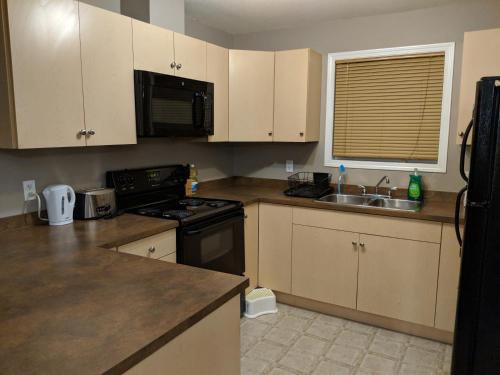 a kitchen with white cabinets and a black stove top oven at Quiet 2 Bed 2 Bath close to Westview Hospital in Stony Plain