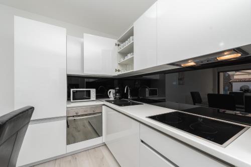 a kitchen with white cabinets and black appliances at Luxury Apartments VilaMaloca in Vir