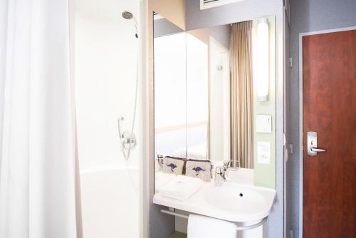 La salle de bains est pourvue d'un lavabo et d'un miroir. dans l'établissement ibis budget Rennes Route de Saint Malo, à Montgermont