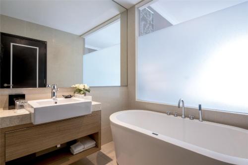 a bathroom with a white tub and a sink at Dorsett Hartamas Kuala Lumpur in Kuala Lumpur