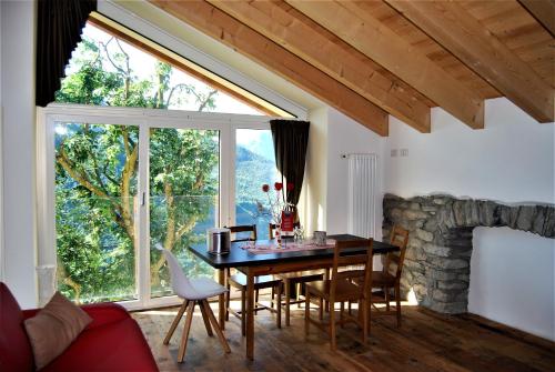 ein Esszimmer mit einem Tisch und einem großen Fenster in der Unterkunft Foresteria B&B Vecchiascuola Pianazzola in Chiavenna
