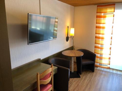 a room with a table and a tv on the wall at Hotel Heuberger Hof, Wehingen in Wehingen