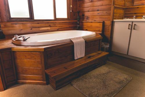 La salle de bains en bois est pourvue d'une baignoire et d'un lavabo. dans l'établissement Oyster Creek Lodge, à Knysna
