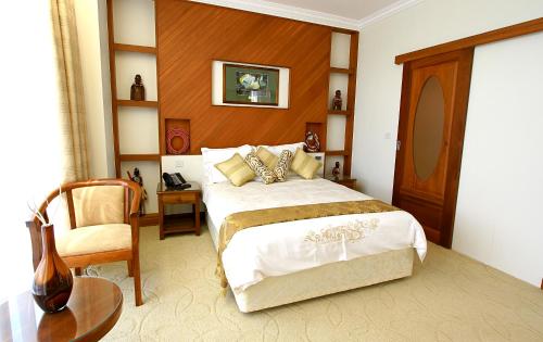 a bedroom with a large bed and a chair at Palace Hotel Arusha in Arusha