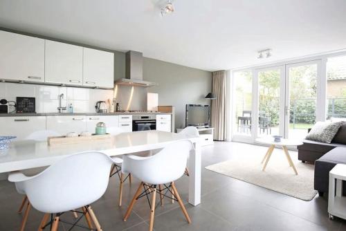 a kitchen with a white table and white chairs at Salt Life Beachhouse in Noordwijk aan Zee