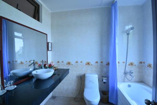 a bathroom with two sinks and a toilet and a tub at Tra Que Riverside Homestay in Hoi An