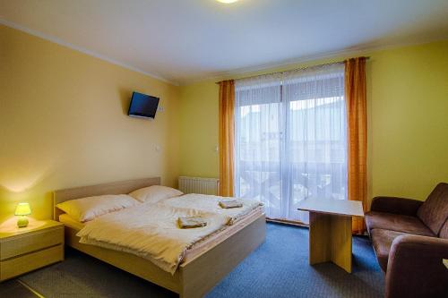 a bedroom with a bed and a window and a chair at Apartmány Sport with Garage in Rokytnice nad Jizerou