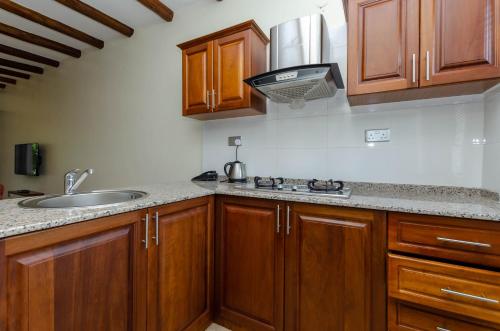 a kitchen with wooden cabinets and a sink at No.5 Boutique Hotel in Entebbe