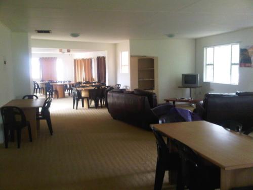 un soggiorno con tavoli e sedie e una sala da pranzo di Sleek Hostel a Johannesburg