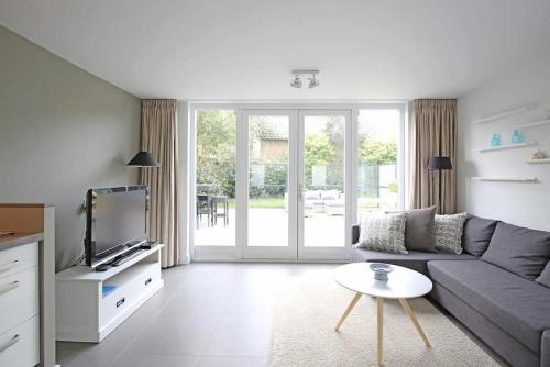 a living room with a couch and a tv at Salt Life Beachhouse in Noordwijk aan Zee