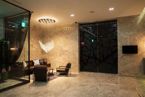 a lobby with a couch and a chair and a television at Hotel Mate Bundang in Seongnam
