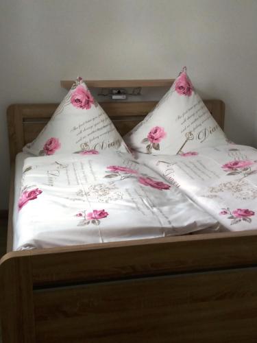 Una cama con sábanas blancas y flores rosas. en Apartments Sport Fudel, en Kurort Oberwiesenthal