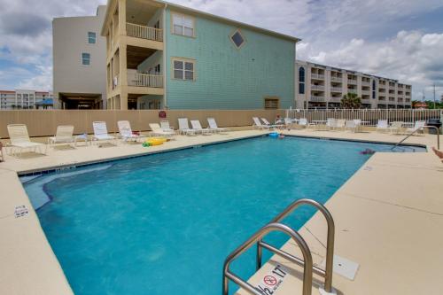 uma grande piscina com cadeiras e um edifício em Romar Beach Condos em Gulf Shores