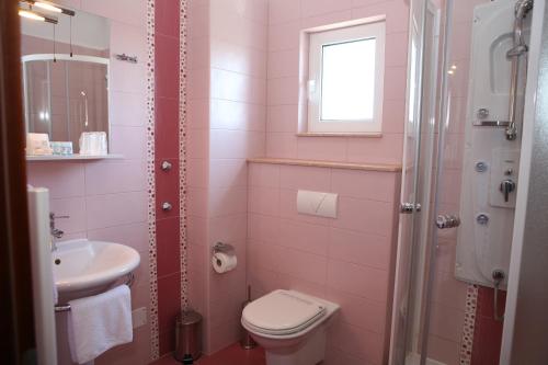 a pink bathroom with a toilet and a sink at Villa Mediterana in Seget Vranjica